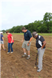 Volunteers and park staff tamp down soil after seeds have been planted
