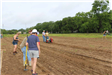 Volunteers and park staff plant seeds while volunteers till soil 