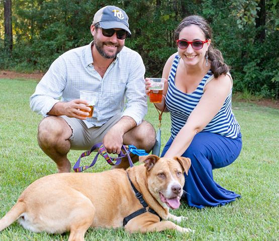 Couple poses with their dog at a happy hour event