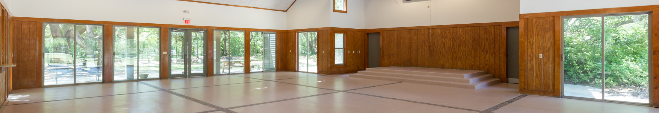 Indoor view of the open space, stage, and windows at the Edisto Hall.