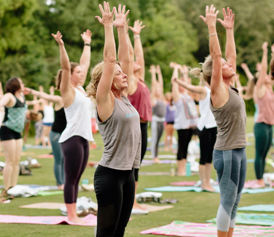 People doing yoga outdoors in a field